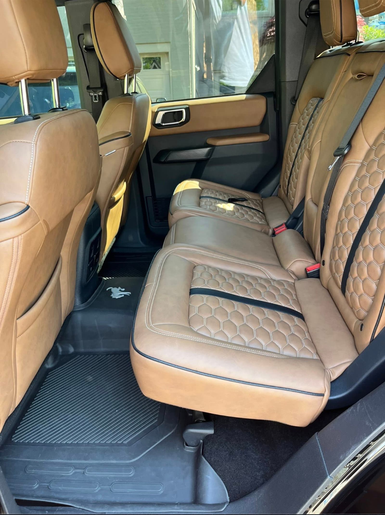 Ford Bronco rear cognac leather seats with honeycomb stitching and clean floor mats.